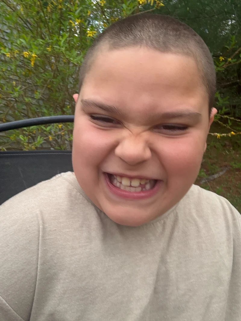 Rocco outdoors with a joyful scrunchy smile, wearing a beige top
